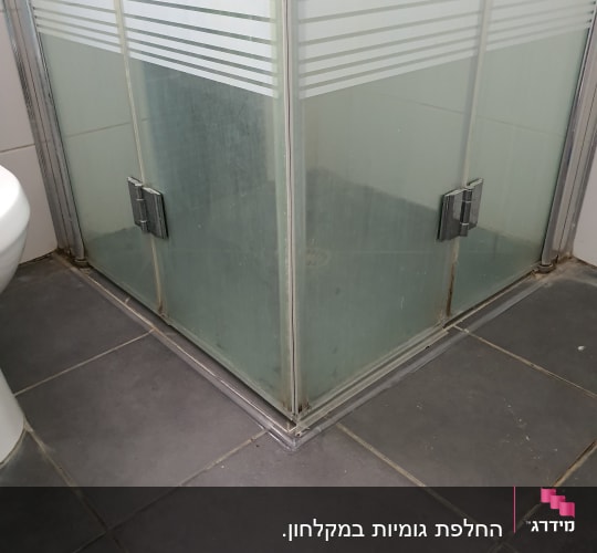 מקלחון זכוכית עם דלתות שקופות ורצפת אריחים אפורה